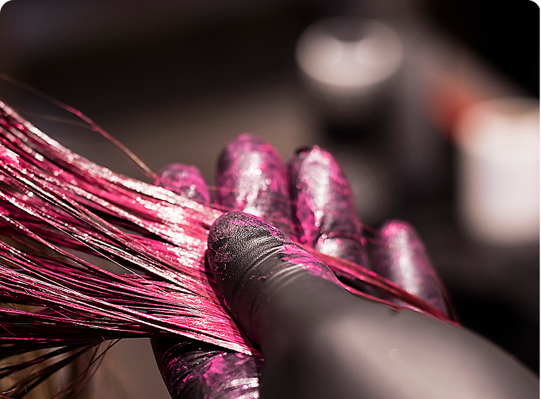 Applying pink hair dye with gloved hand