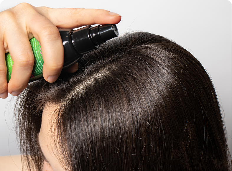 Person using hair spray on roots