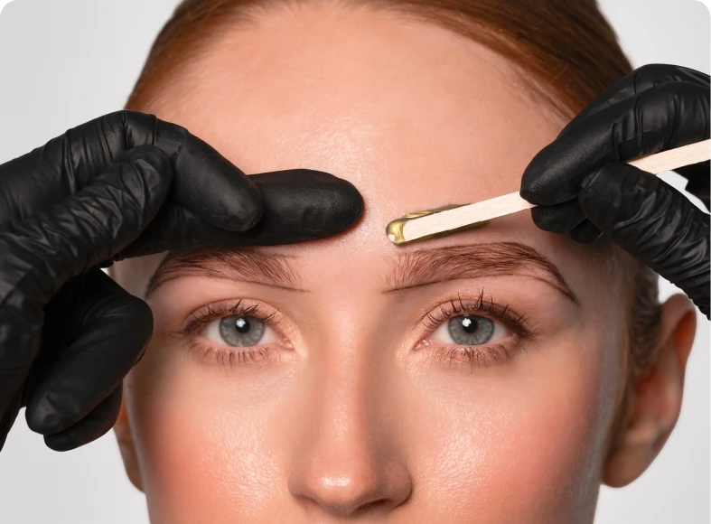 Beautician applying wax to eyebrows