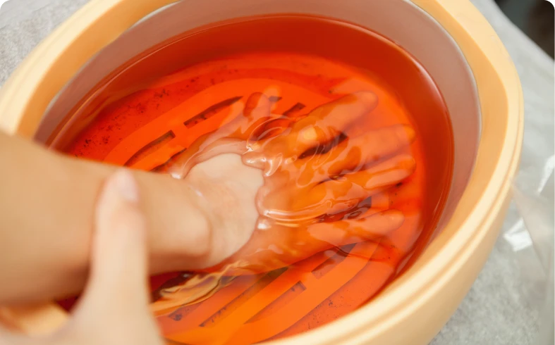 Hand in warm orange wax bath