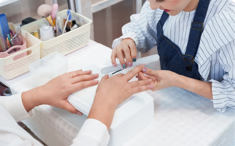 Nail technician filing customer's nails